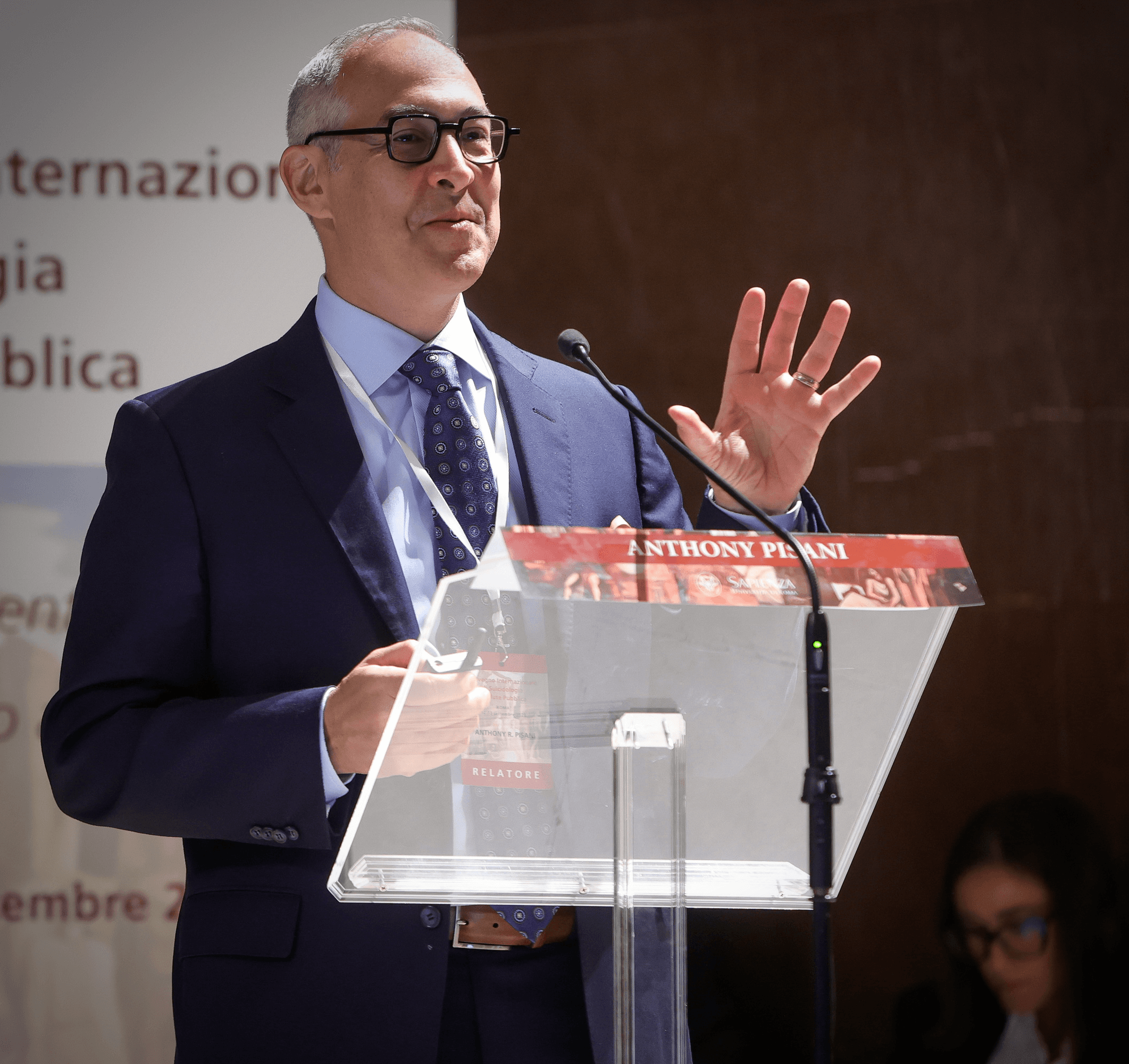 Tony Pisani speaking at a lectern during a conference presentation.